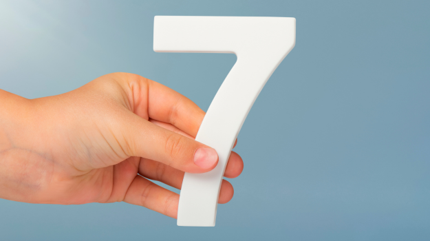 Image of hand holding the number seven.